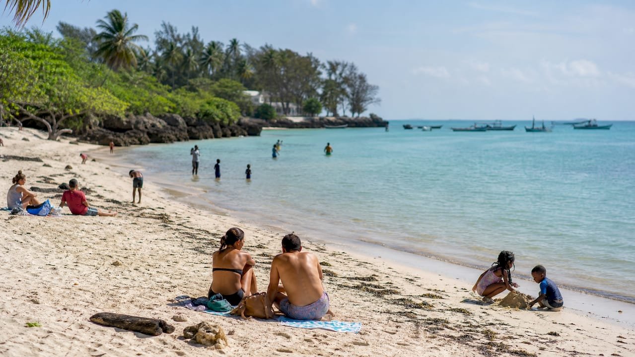 Una famiglia si gode una giornata di relax in una tranquilla e protetta spiaggia di Diani, circondata da acque calme e un’atmosfera serena.