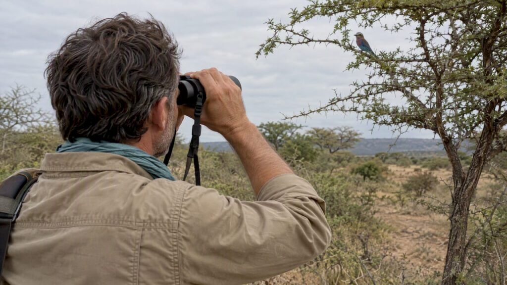 Un appassionato di birdwatching che osserva un uccello con il binocolo