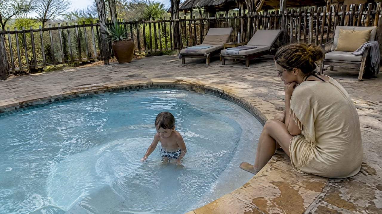 Un genitore controlla un bambino nella piscina del lodge, Bambini nei lodge safari