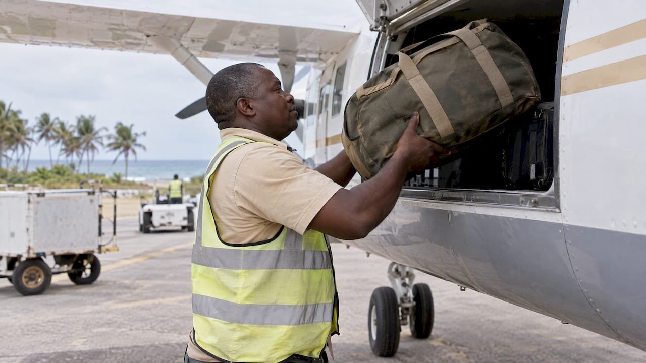 Un addetto carica una borsa morbida su un piccolo aereo
